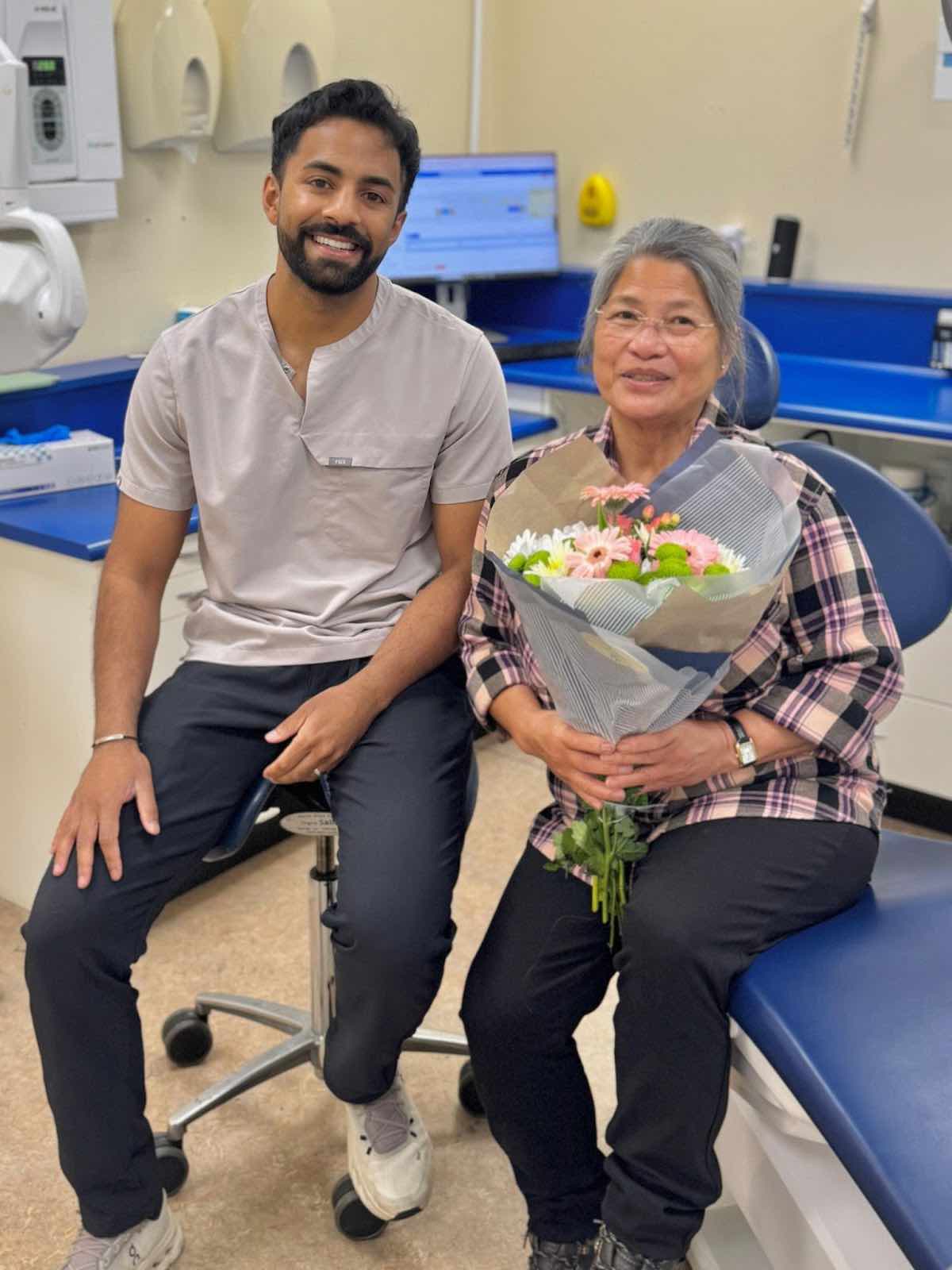 Patient holding flowers with dentist Dr Nev Jeyakumar after successful dental implant treatment