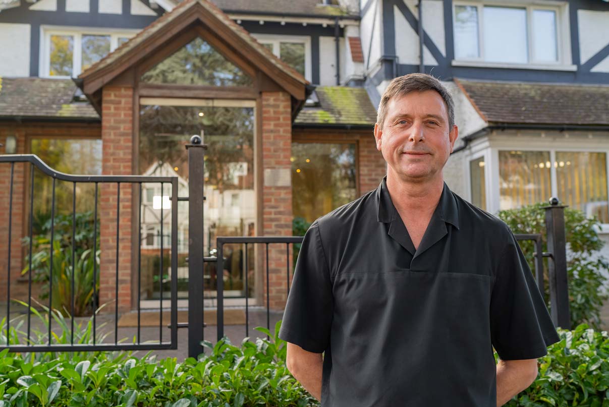 An experienced dentist standing in front of a modern dental surgery.