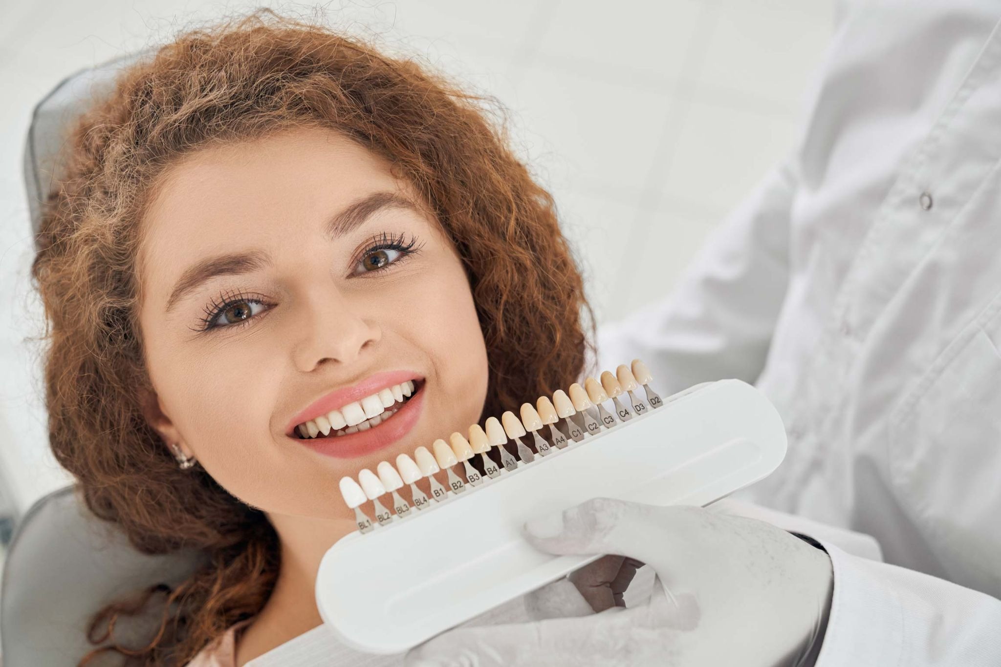 Patient comparing tooth shades with a dentist before cosmetic dental treatment