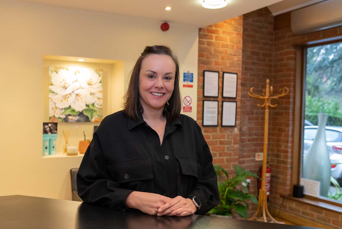 Welcoming dental treatment coordinator smiling at the camera in waiting area.