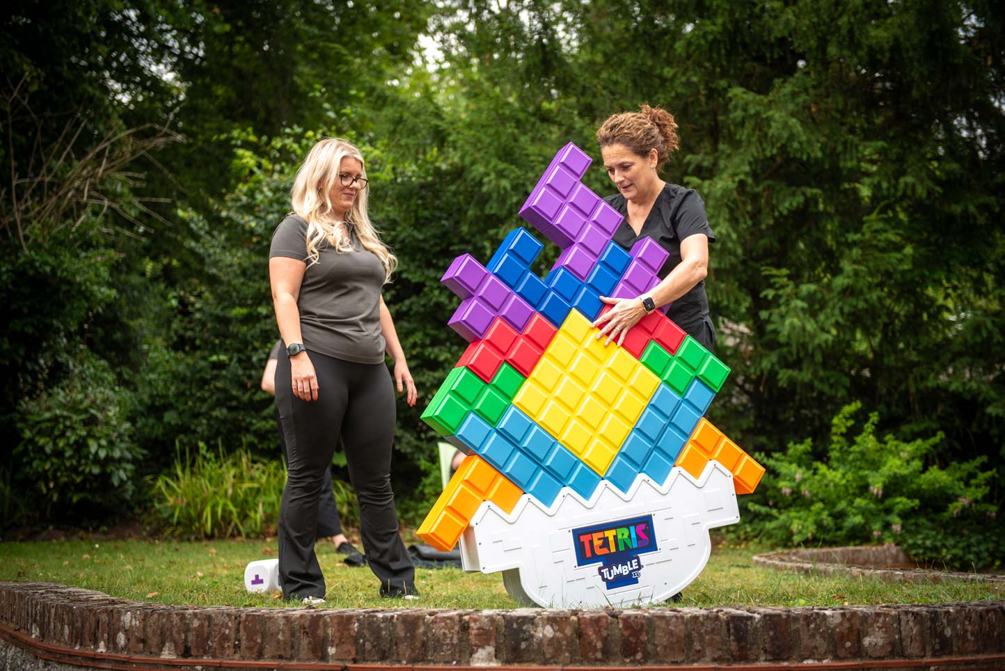 Team members Kayleigh Woolacott and Vicky Harris playing a team-building game outdoors