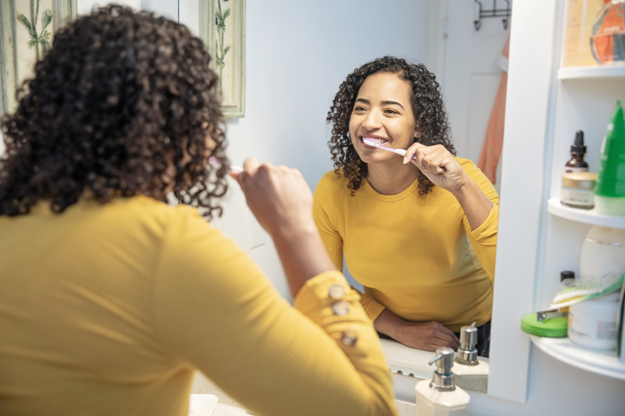 Woman brushing teeth at home to maintain professional teeth whitening results and good oral hygiene