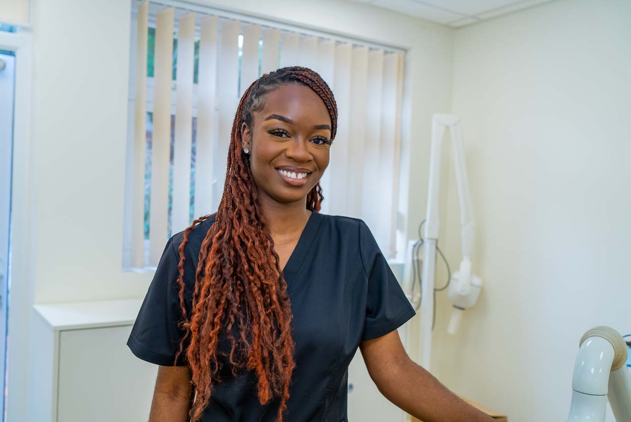 A smiling gentle dental expert stands in the dental surgery.