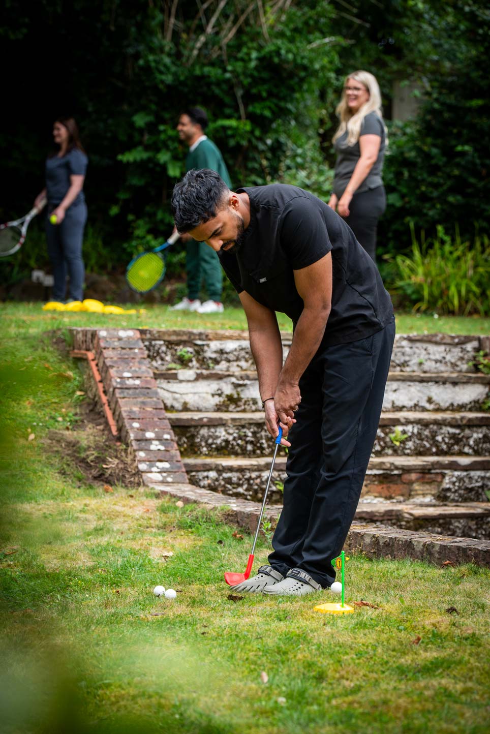Dentist Nev Jeyakumar playing golf outdoors, symbolising confidence and lifestyle benefits after SmileFast veneers