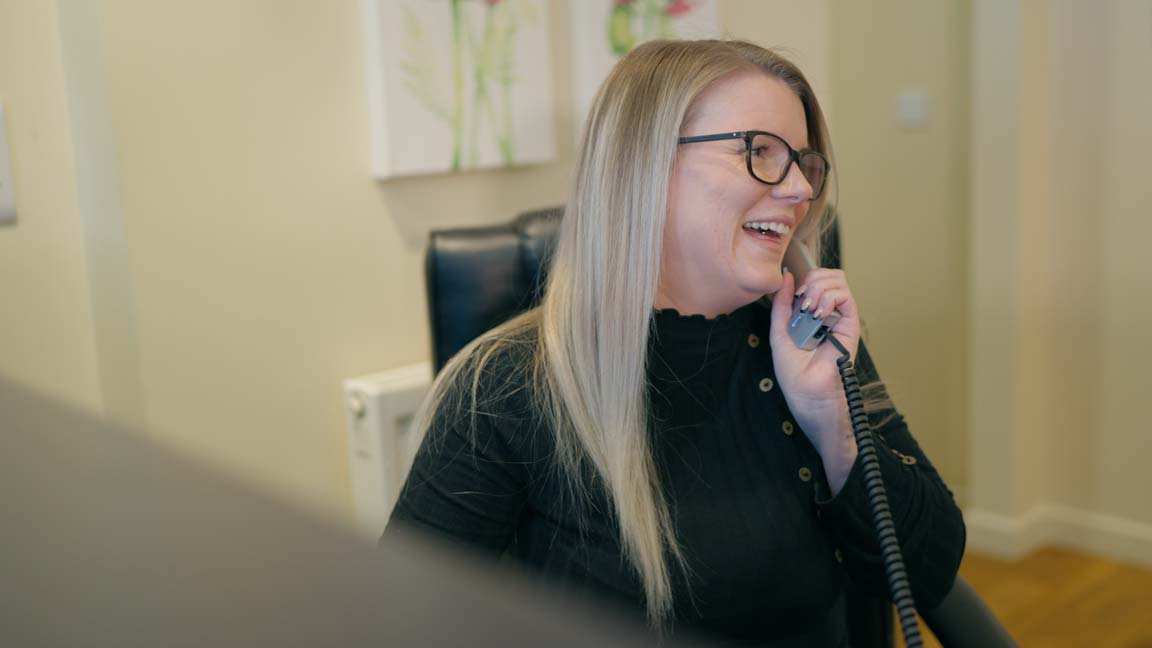 A smiling female dental receptionist on the telephone.