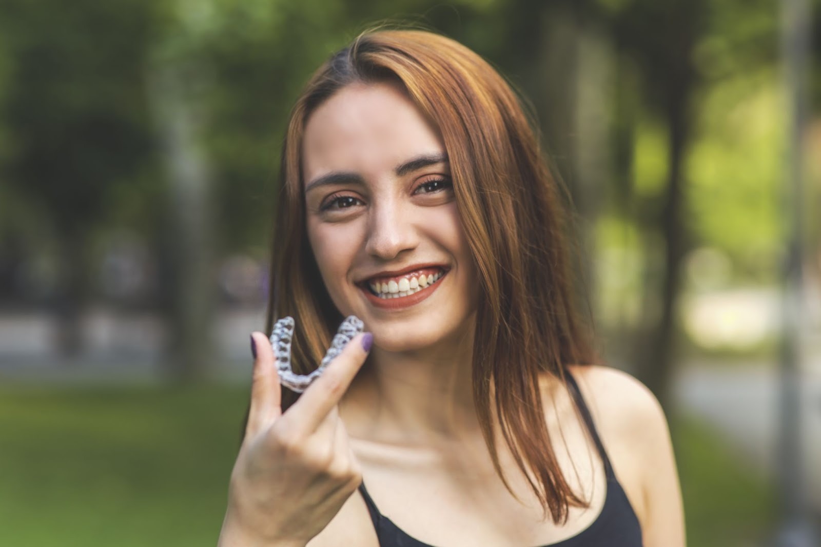 Patient holding Invisalign clear aligner as part of a smile makeover at a cosmetic dentist in Purley