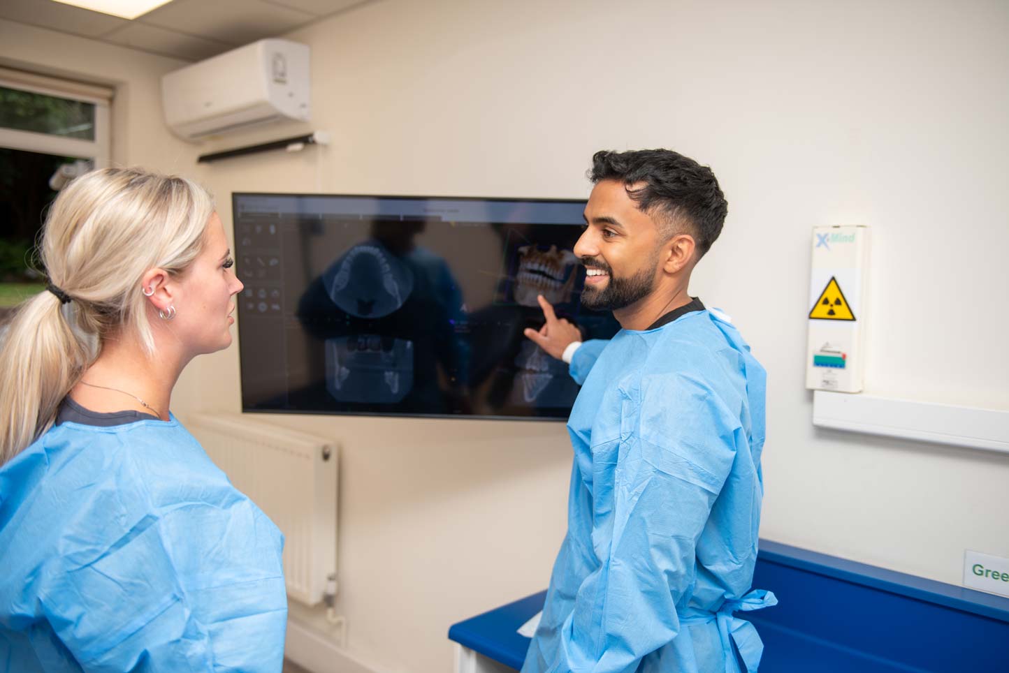 Dentist Dr Nev Jeyakumar reviewing a dental scan with a patient during a dental implant consultation