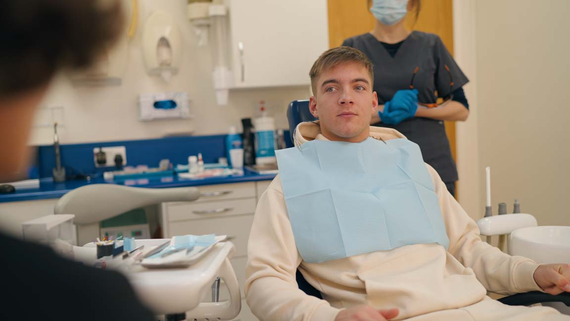Young man sitting in a dental chair during assessment at Foxley Lane Dental, preparing for a potential dental implant treatment.