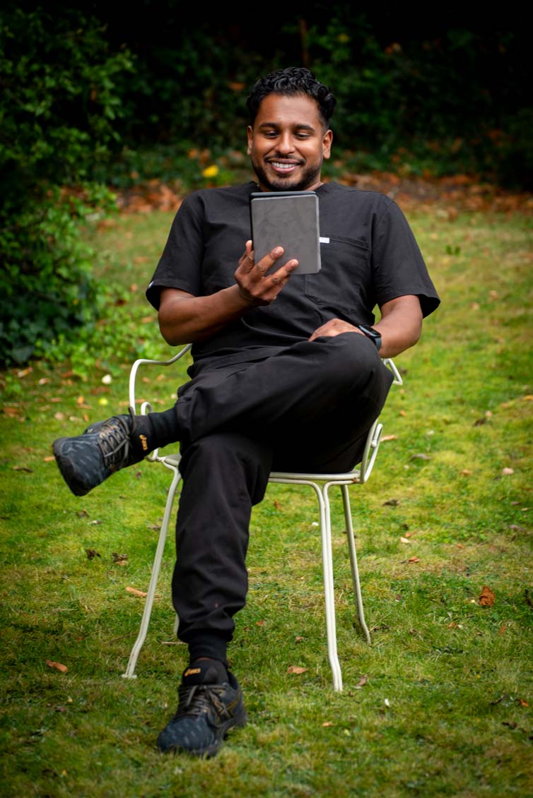 Dentist Dr Jamie Sasikumar at Foxley Lane Dental discussing cosmetic dentistry options with a patient in the Purley garden setting.