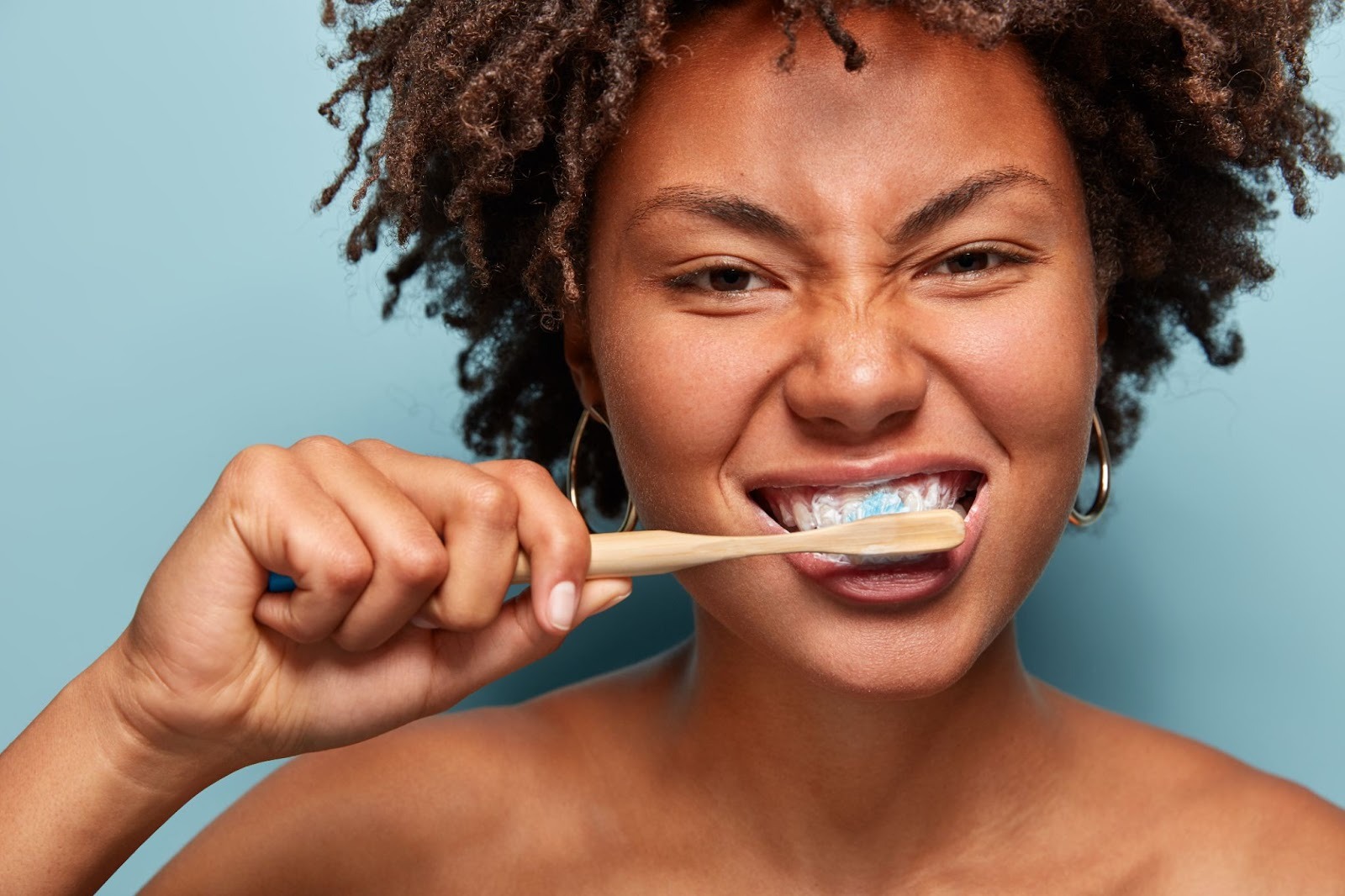 Person brushing teeth with fluoride toothpaste and bamboo toothbrush, promoting healthy enamel care and daily oral hygiene - Foxley Lane Dental, Purley.
