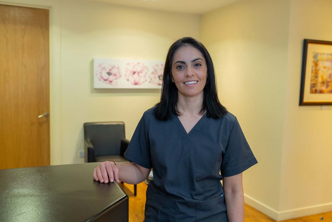A welcoming dentist smiles at the camera from the reception area.